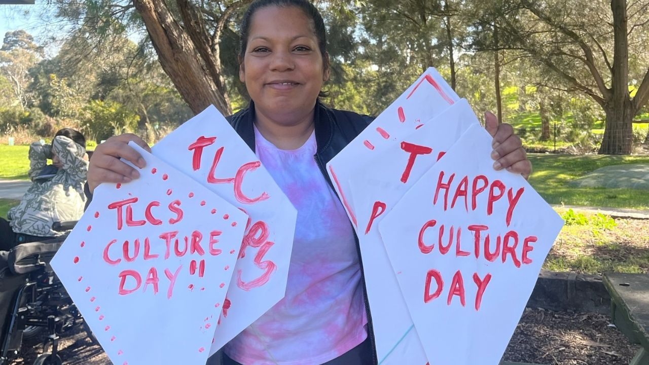 a member of the tlc team holding paper kites that bear the texts, TLC Culture Day and Happy Culture Day