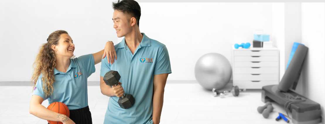 Two of our skilled physiotherapists in Sydney, NSW, Sarah and Peter, share a cheerful moment, smiling at each other. Sarah holds a ball, while Peter holds a small dumbbell.