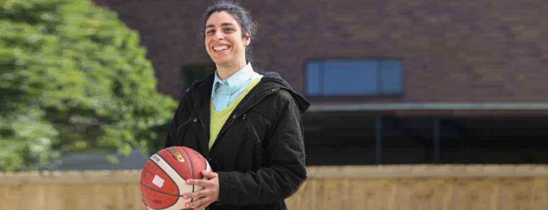 A happy female participant holds a basketball ball with a bright smile, showcasing the enjoyment and inclusivity of TLC Disability Services' engaging day programs in Sydney, NSW.